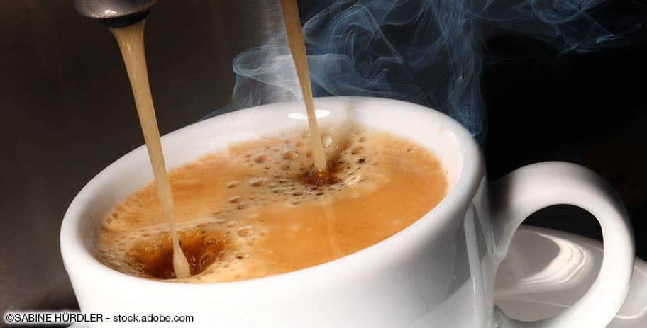Kaffee fliesst von der Kaffeemaschine in eine Tasse.