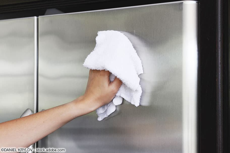 Ein Kühlschrank wird äusserlich mit einem weichen, weissen Lappen gereinigt.