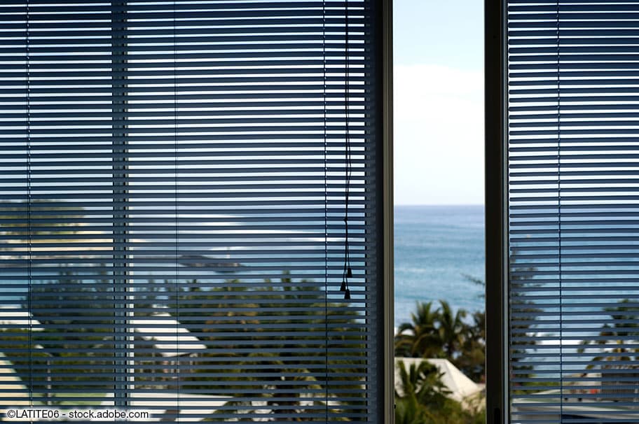Offene Fenster, im Hintergrund befinden sich Palmen und das Meer.