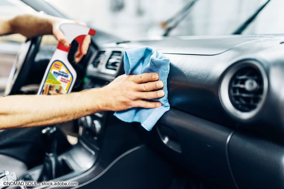 Lederarmaturen im Auto werden mit einem blauen Putzlappen gereinigt.