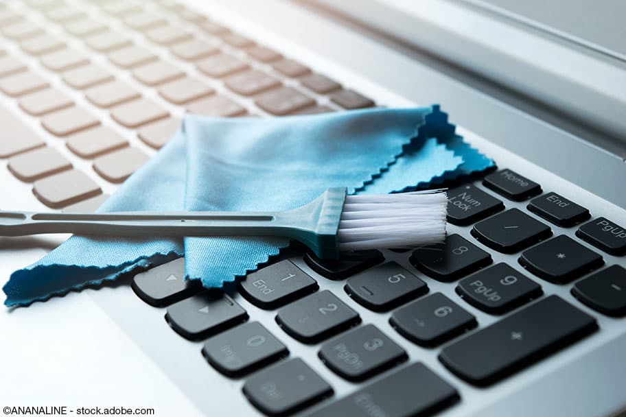 Pinsel und blaues Reinigungstuch auf einer modernen Tastatur mit schwarzen Tasten.