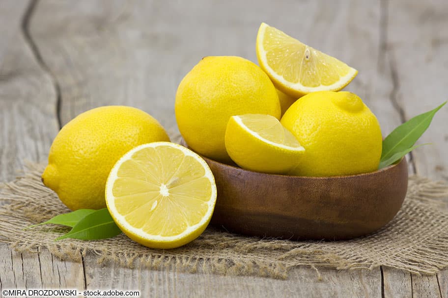 Frische Zitronen in einer braunen Schale.